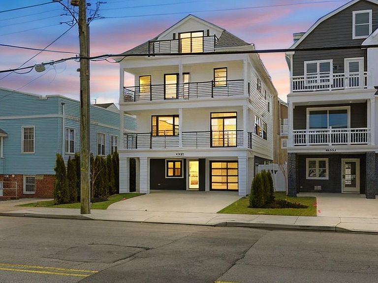 6302 Ventnor Avenue at dusk, three-story coastal contemporary with warm-lit windows under a pink twilight sky